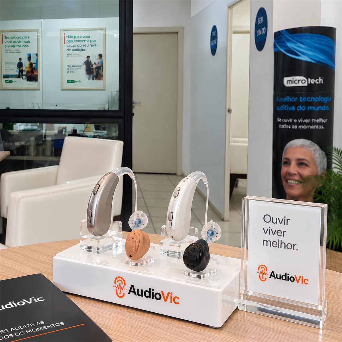 Expositor da AudioVic com diferentes tipos de aparelho auditivo em exposição, ao lado do material da loja