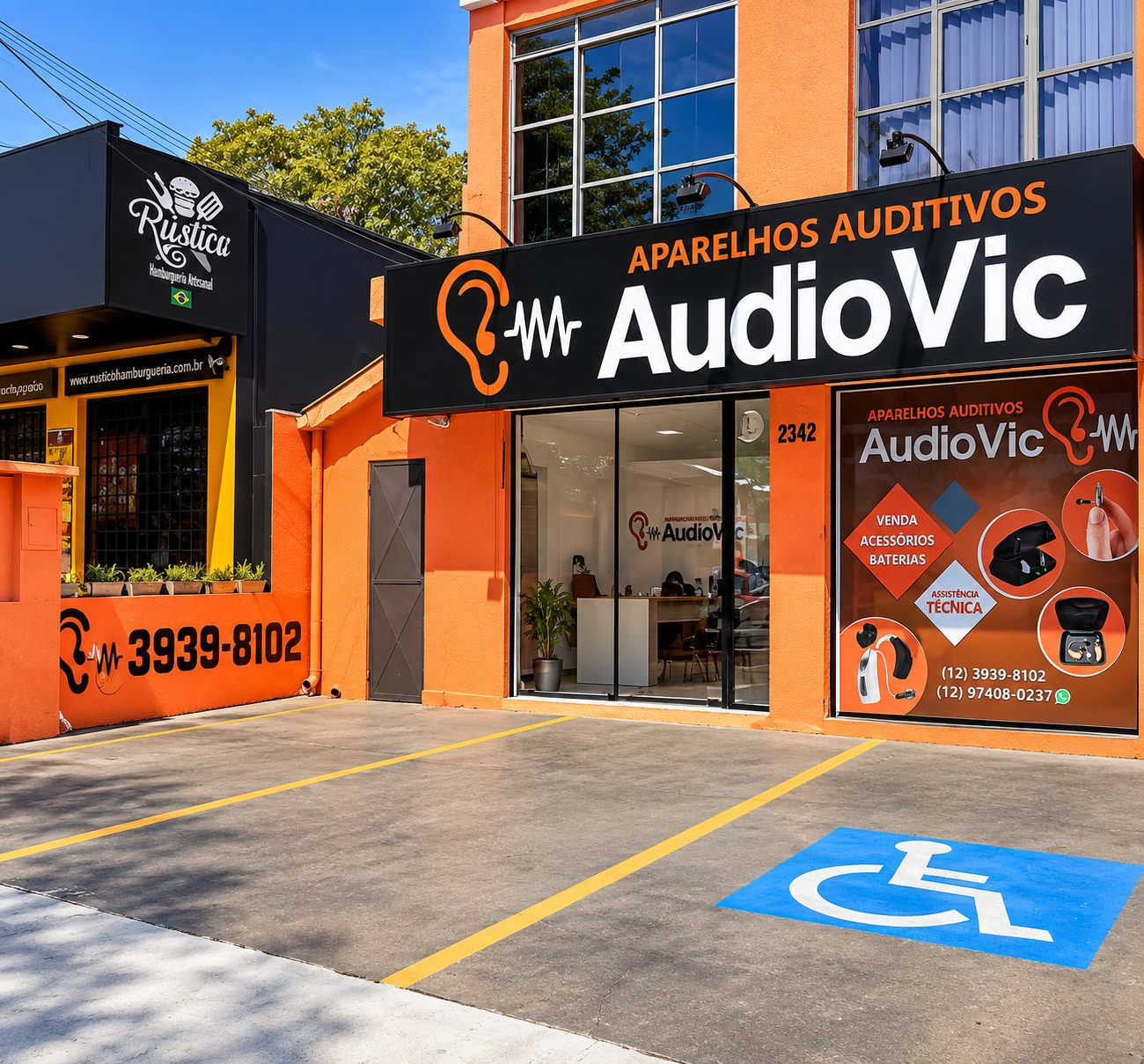 Vista lateral da AudioVic mostrando o estacionamento em frente à loja, com vaga de acessibilidade demarcada